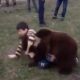 Chechen boy wrestling with bear on lawn in front of whole village
